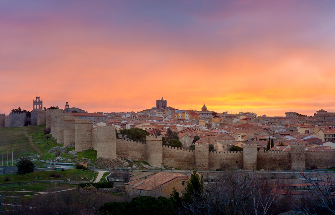 Panoramic view of Avila's medieval town walls at sunset from Los Cuatro Postes, Spain.