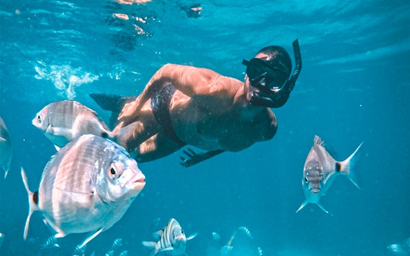 Man snorkeling among fish in the Blue Lagoon, Angra dos Reis.