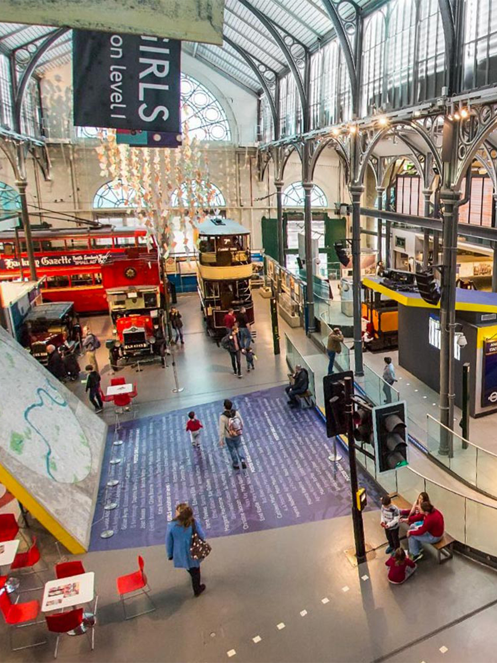 Interior view of London Transport Museum with vintage buses and visitors exploring exhibits.