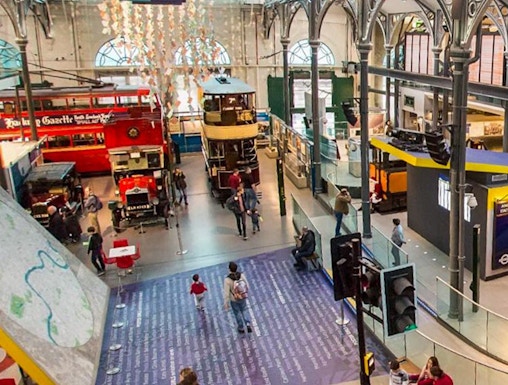Interior view of London Transport Museum with vintage buses and visitors exploring exhibits.