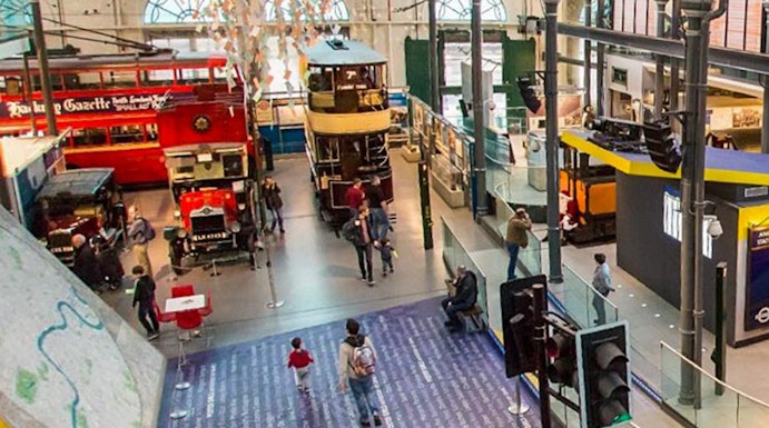 Interior view of London Transport Museum with vintage buses and visitors exploring exhibits.