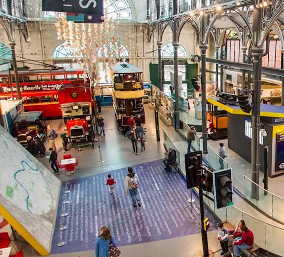 Interior view of London Transport Museum with vintage buses and visitors exploring exhibits.