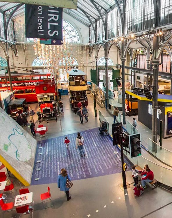 Interior view of London Transport Museum with vintage buses and visitors exploring exhibits.