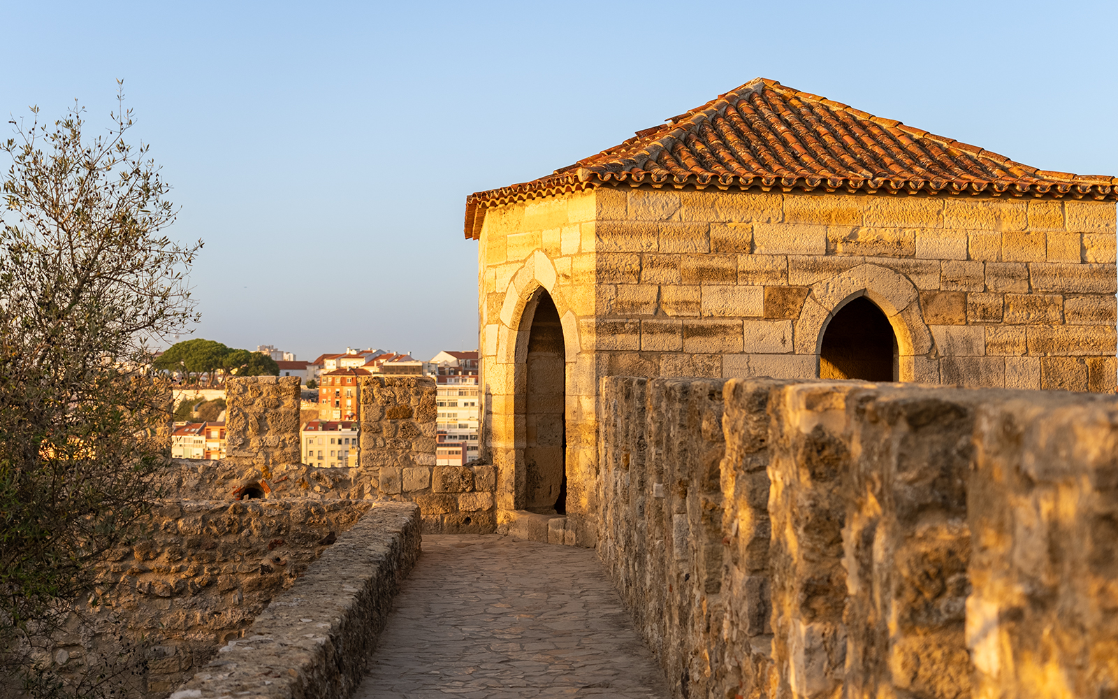 St. George’s Castle stone walkway and tower in Lisbon at sunset.