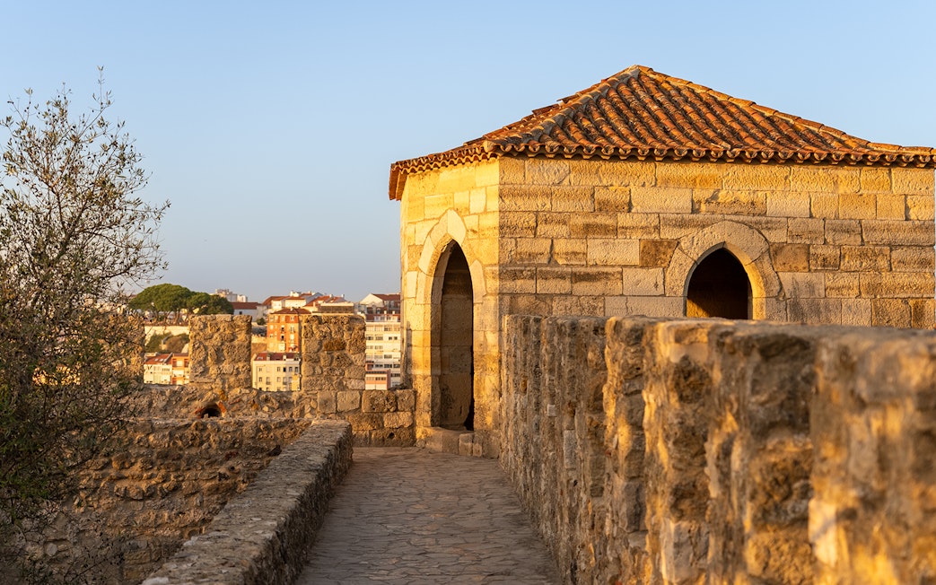St. George’s Castle stone walkway and tower in Lisbon at sunset.