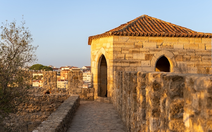 St. George’s Castle stone walkway and tower in Lisbon at sunset.