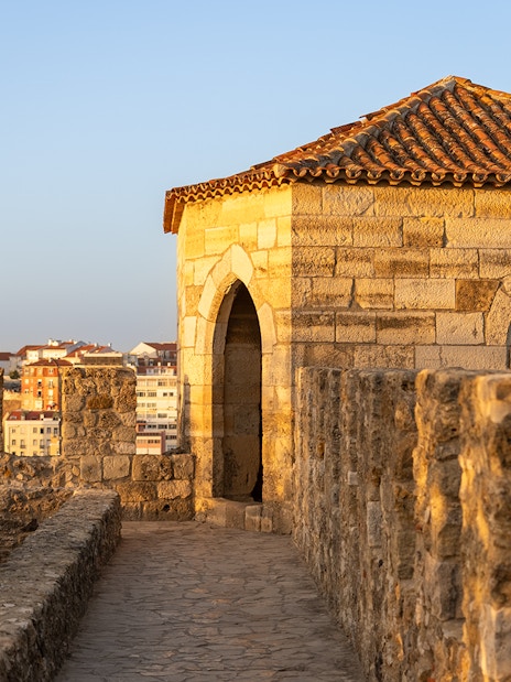 St. George’s Castle stone walkway and tower in Lisbon at sunset.