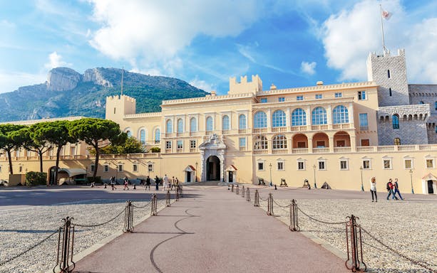 Prince’s Palace in Monaco with tourists walking in the courtyard.