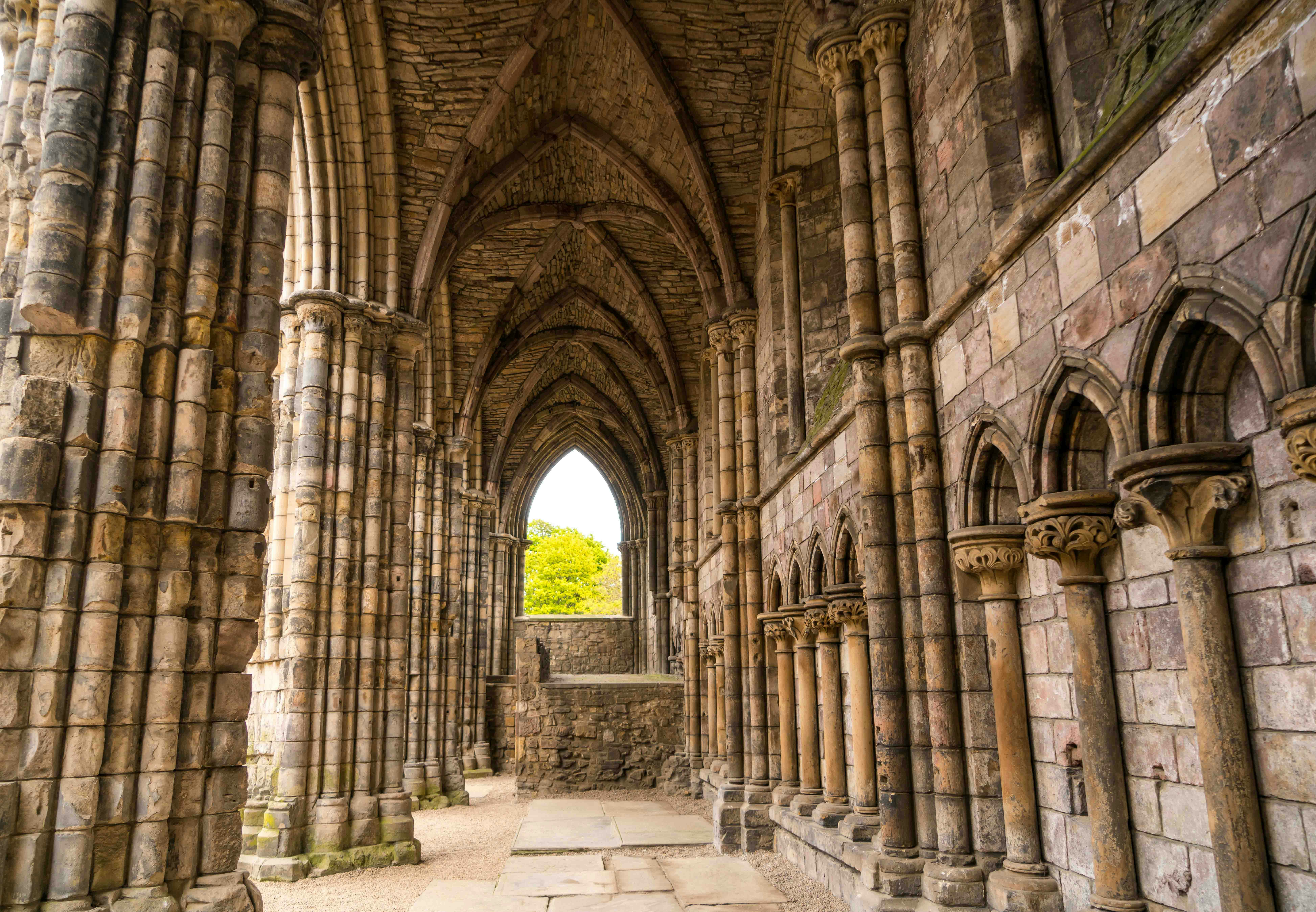 Ruins of the Abbey at Palace of Holyroodhouse, Edinburgh, with stone arches and columns.