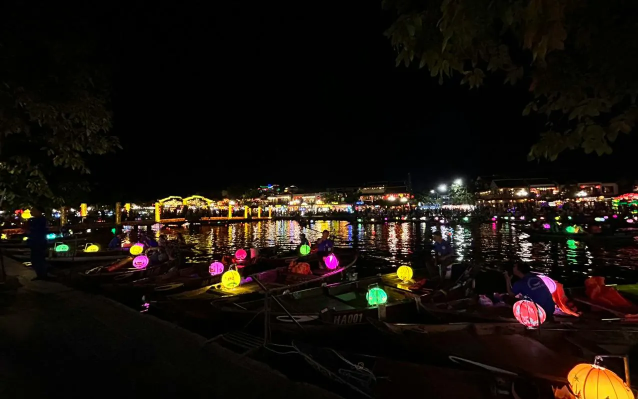 Boat ride with colorful lanterns reflecting on water, offering free herbal drink in Dubai.