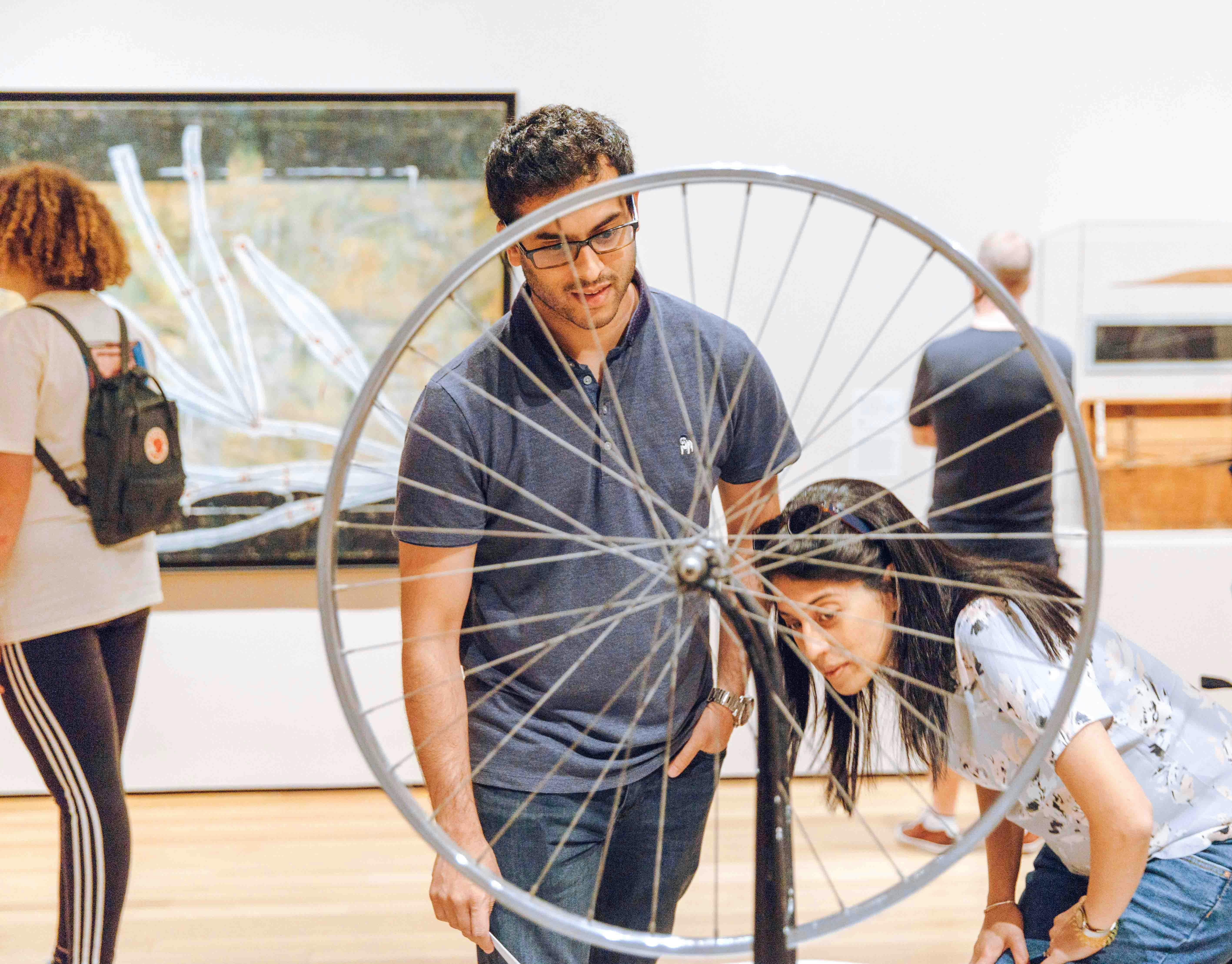 Visitors viewing Marcel Duchamp artwork at NYC MoMA exhibition.