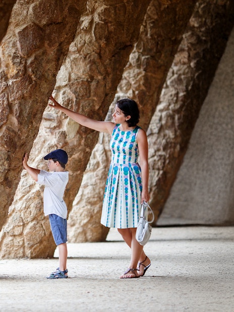 Mother and son exploring stone columns in Park Guell, Barcelona.