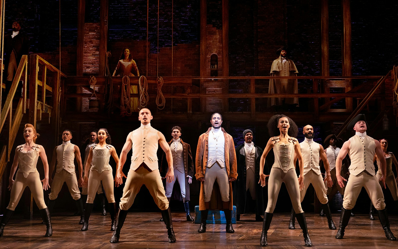 Cast performing a scene from the musical Hamilton on stage.