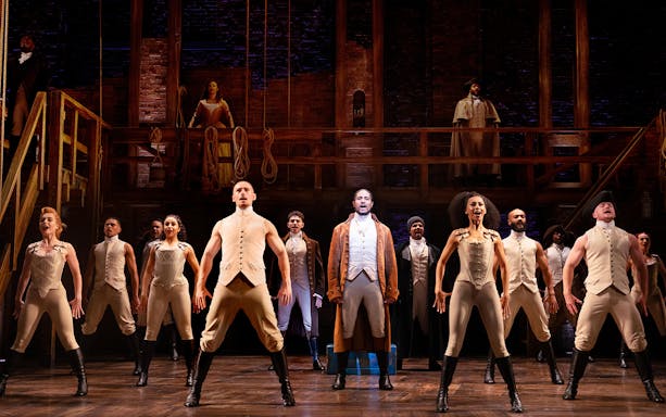 Cast performing a scene from the musical Hamilton on stage.
