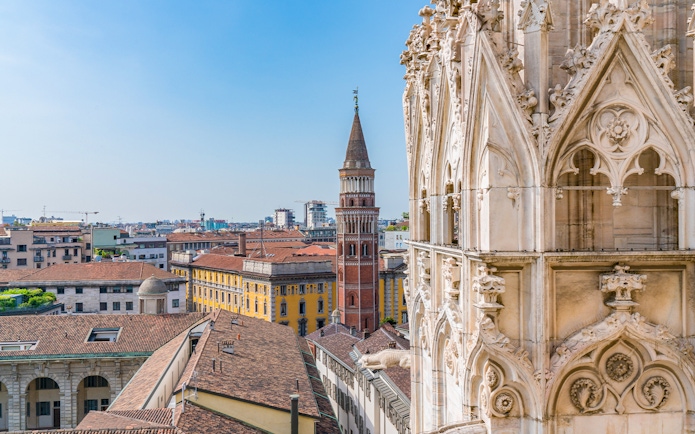 Milan Cathedral rooftop view with cityscape and historic tower.