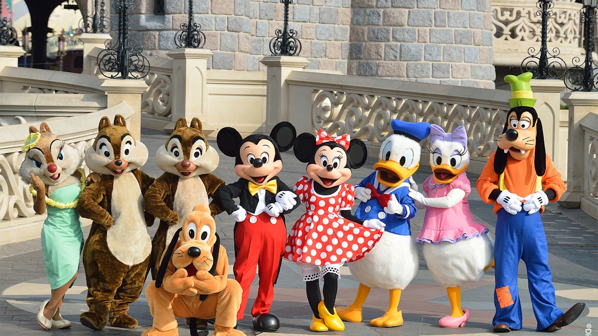 Disney characters posing in front of a castle at Disneyland Paris.