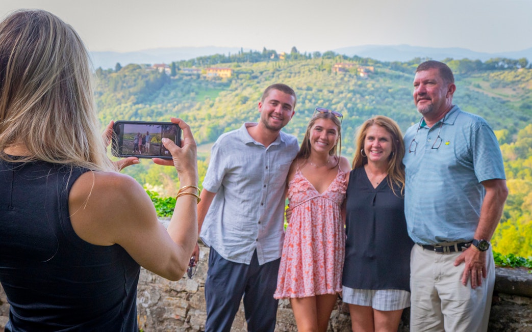 Tourists posing for a photo with Tuscan hills in the background during a semi-private Tuscany tour.