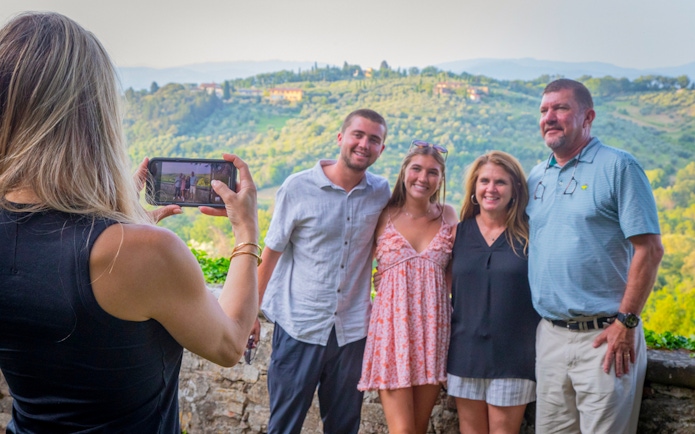 Tourists posing for a photo with Tuscan hills in the background during a semi-private Tuscany tour.