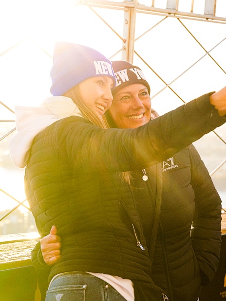 Guests taking a selfie on the Empire State Building's observation deck with a viewfinder nearby.