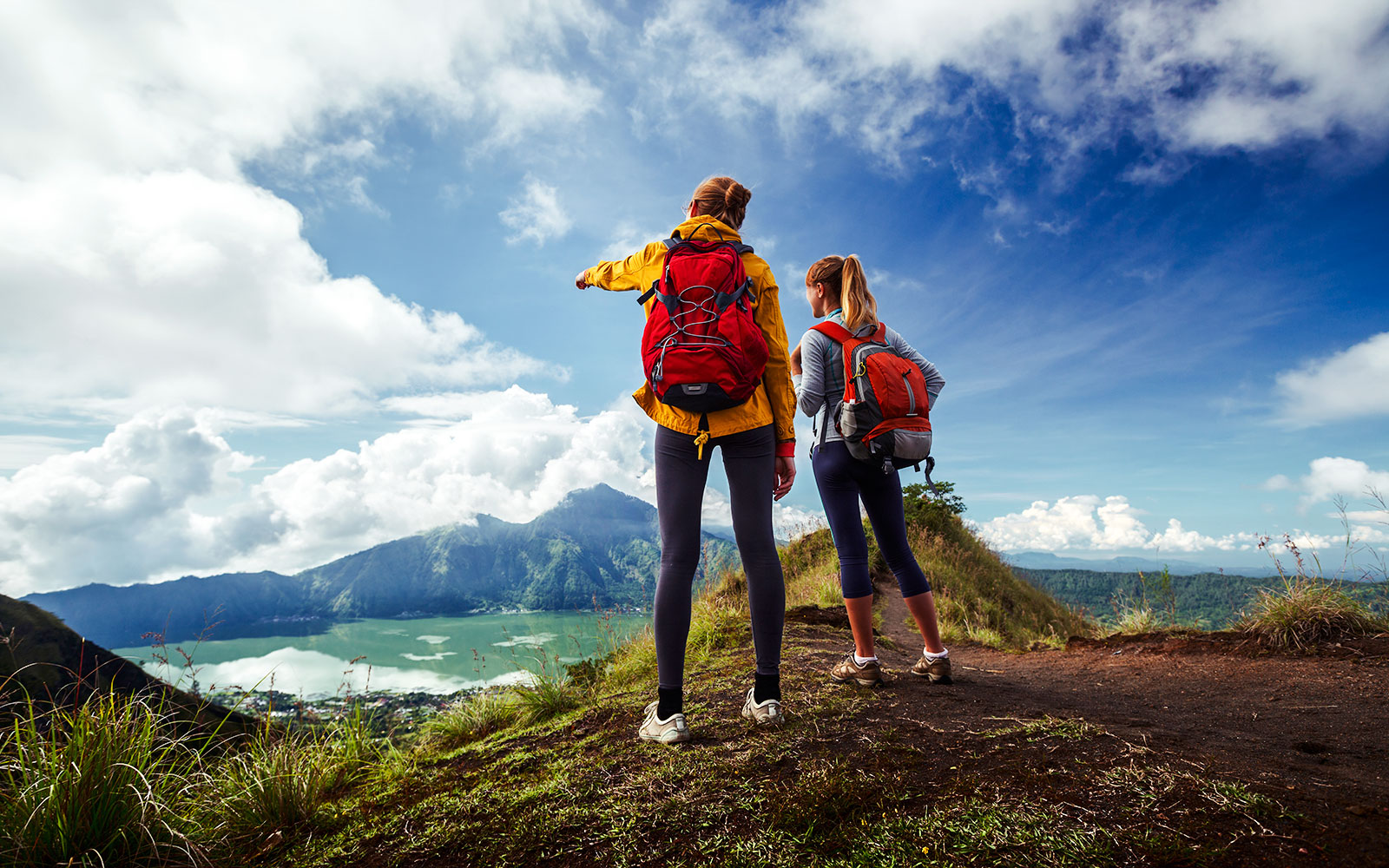 Hikers with backpacks overlooking Mount Batur and Lake Batur in Bali.
