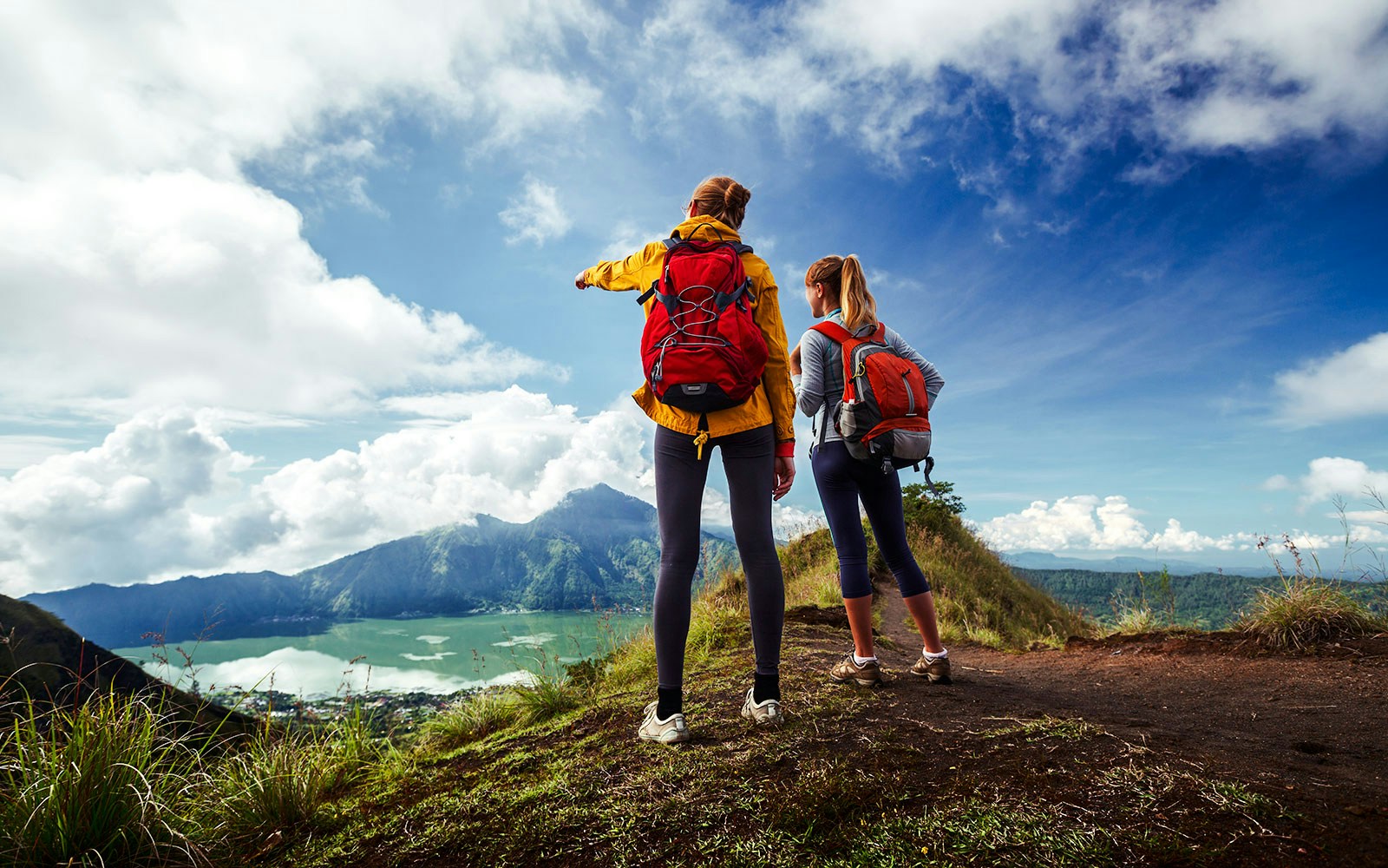 Hikers with backpacks overlooking Mount Batur and Lake Batur in Bali.