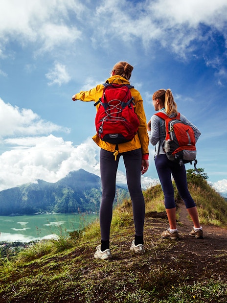Hikers with backpacks overlooking Mount Batur and Lake Batur in Bali.