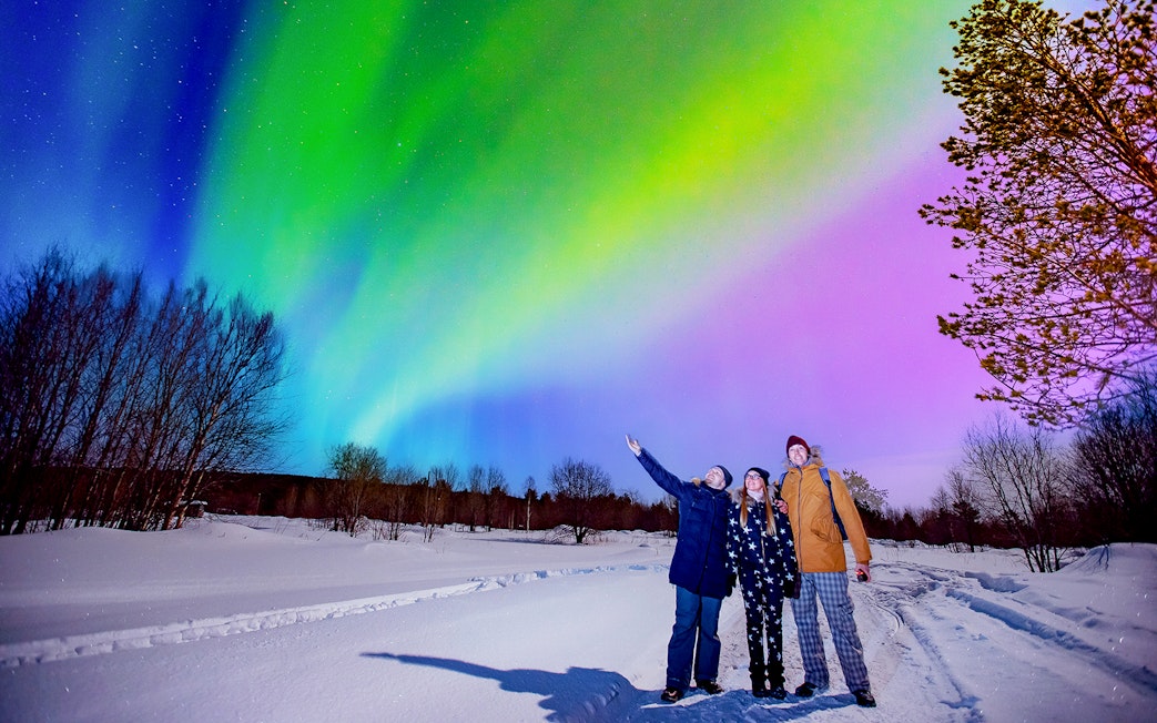 Tourists enjoying Northern Lights at Blue Lagoon geothermal spa, Iceland.