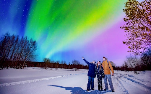 Tourists enjoying Northern Lights at Blue Lagoon geothermal spa, Iceland.