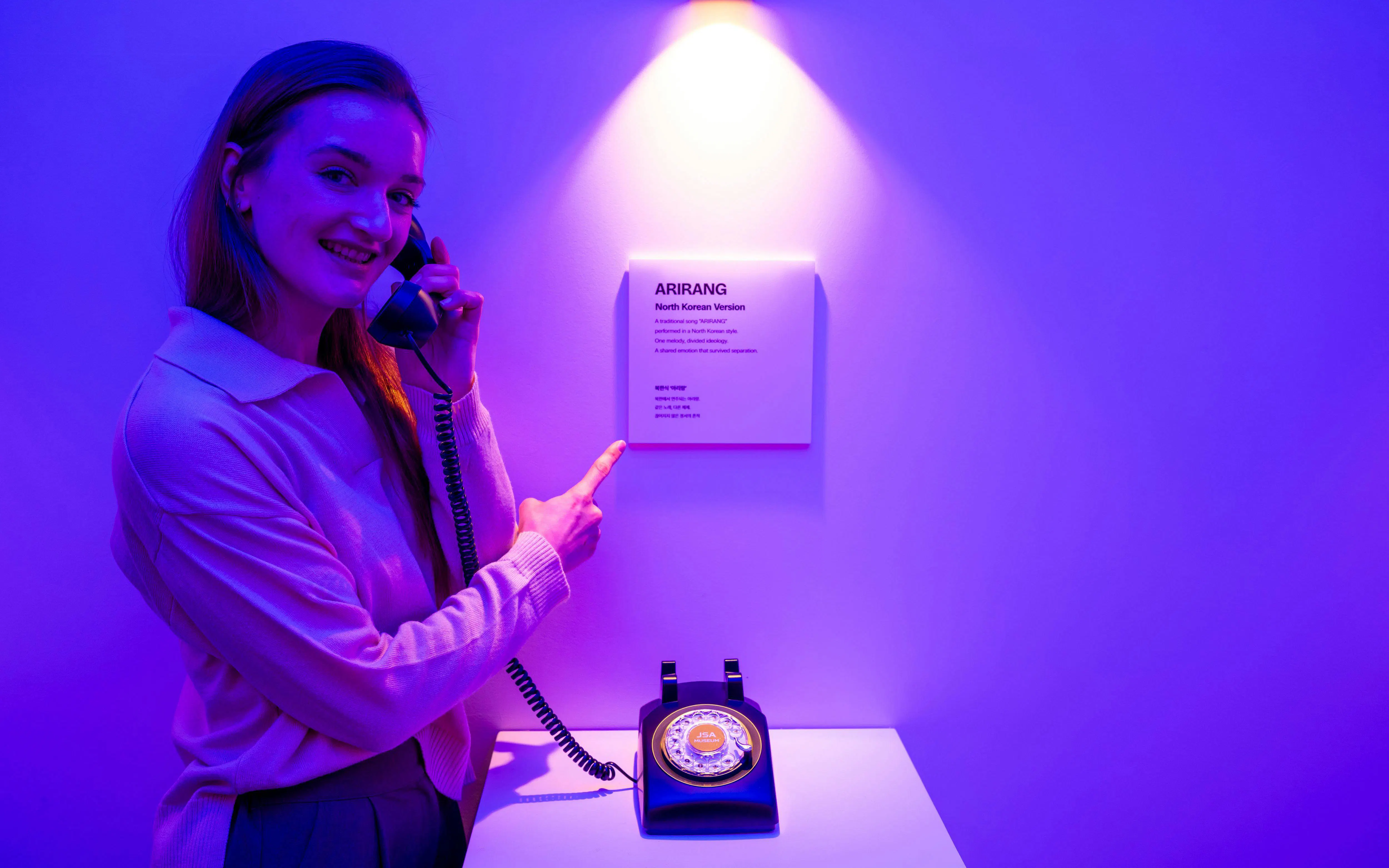 Person using a vintage phone at JSA Museum exhibit during Half-Day DMZ Tour from Seoul.