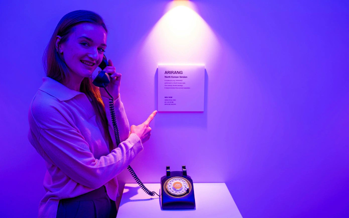 Person using a vintage phone at JSA Museum exhibit during Half-Day DMZ Tour from Seoul.