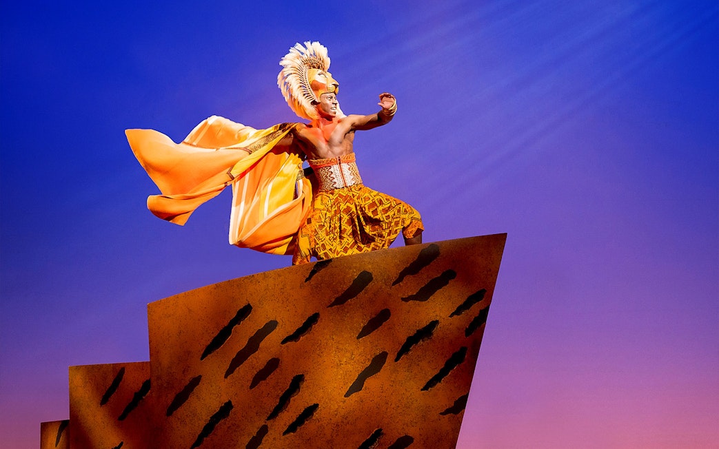 Performer in lion costume on stage during The Lion King musical.