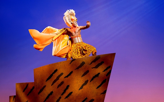Performer in lion costume on stage during The Lion King musical.