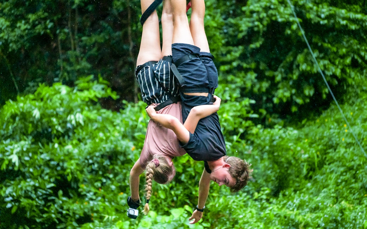 Two people bungy jumping in Cairns rainforest.