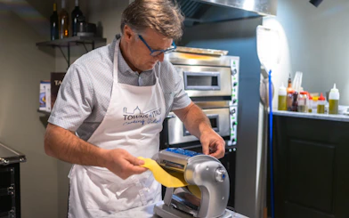 Man making pasta with a machine during a Milan cooking class.