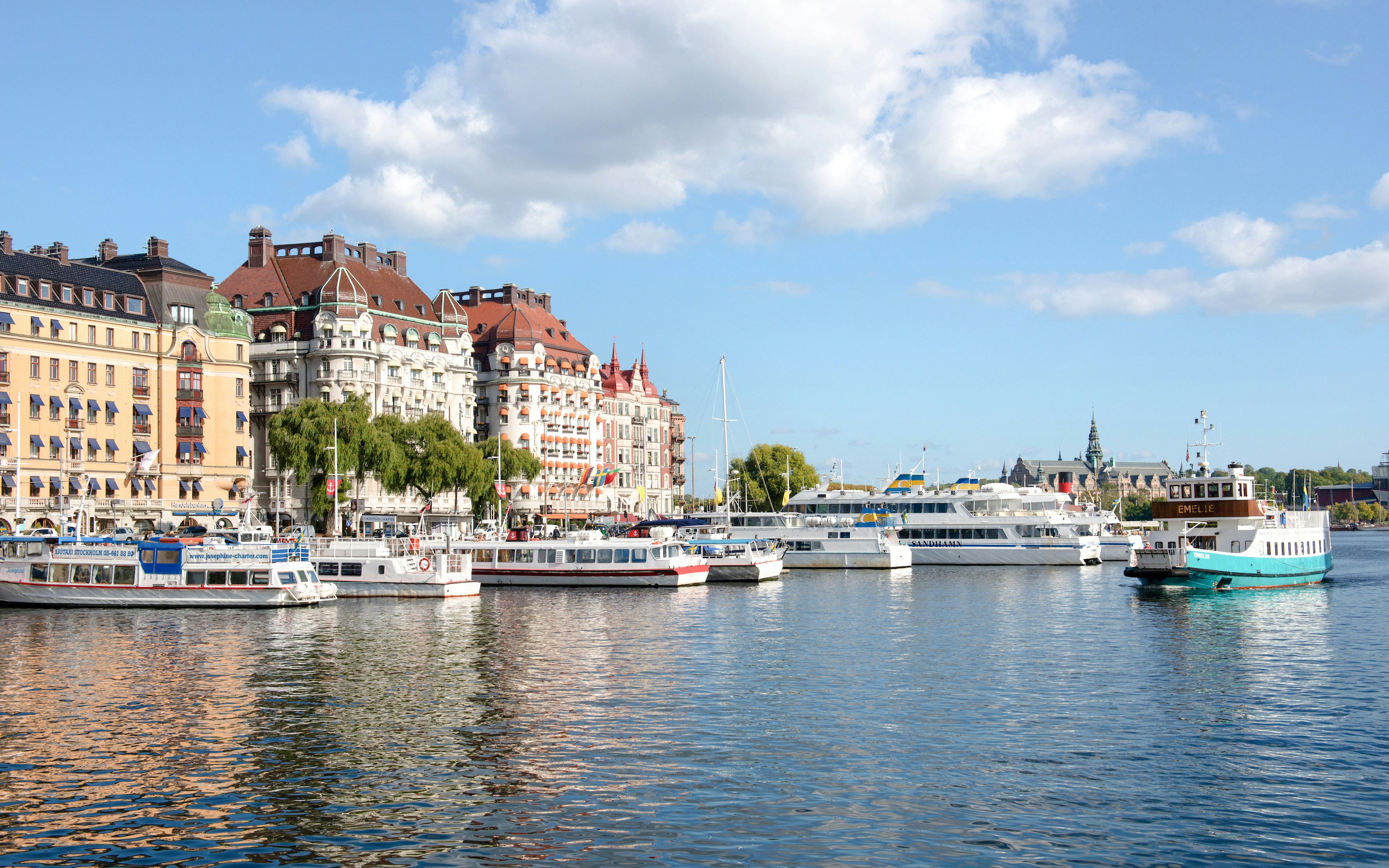 Boats docked along Strandvägen in Stockholm with historic buildings in the background.