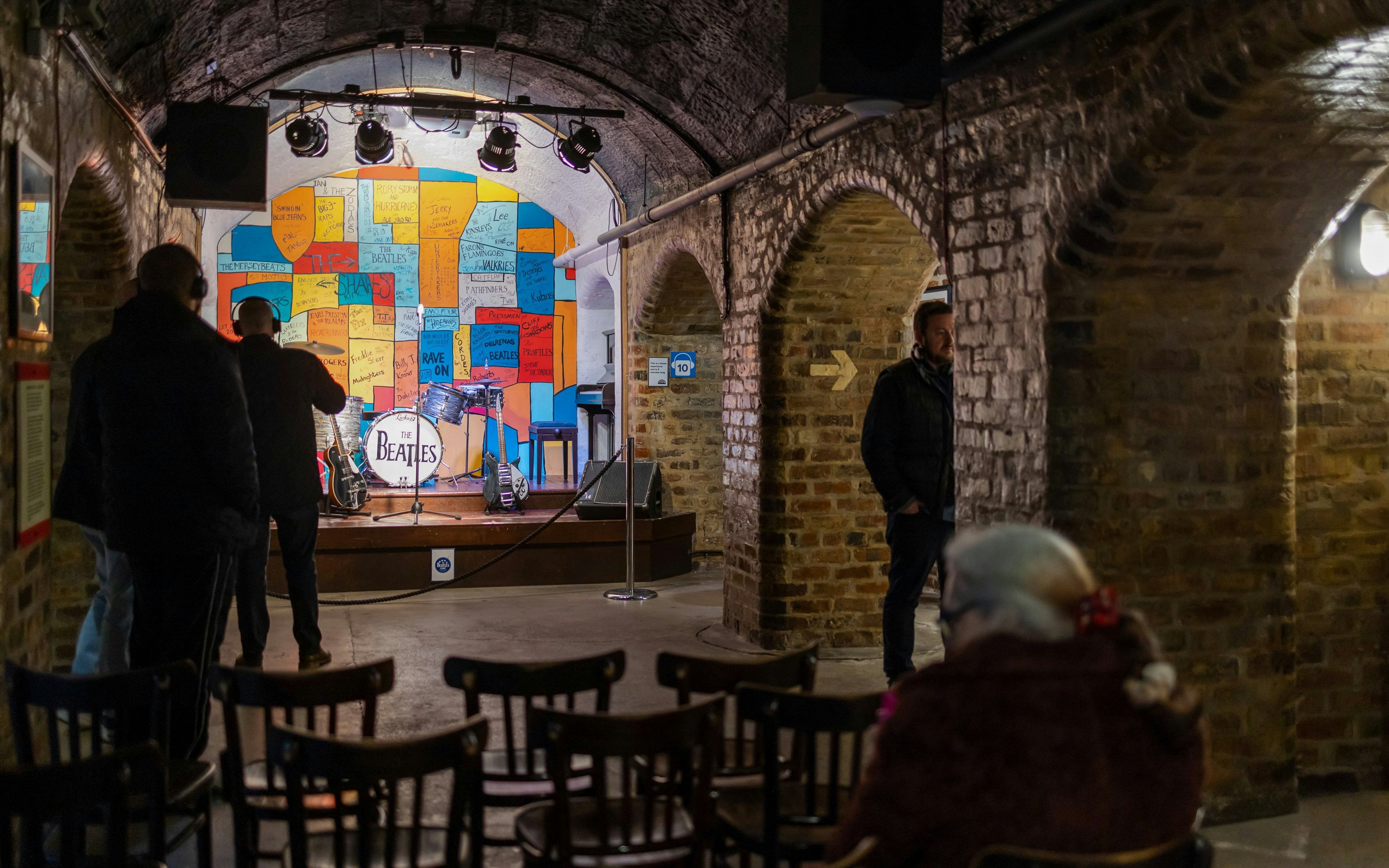 Beatles Story exhibit with stage, instruments, and colorful wall in Liverpool.