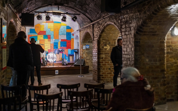 Beatles Story exhibit with stage, instruments, and colorful wall in Liverpool.