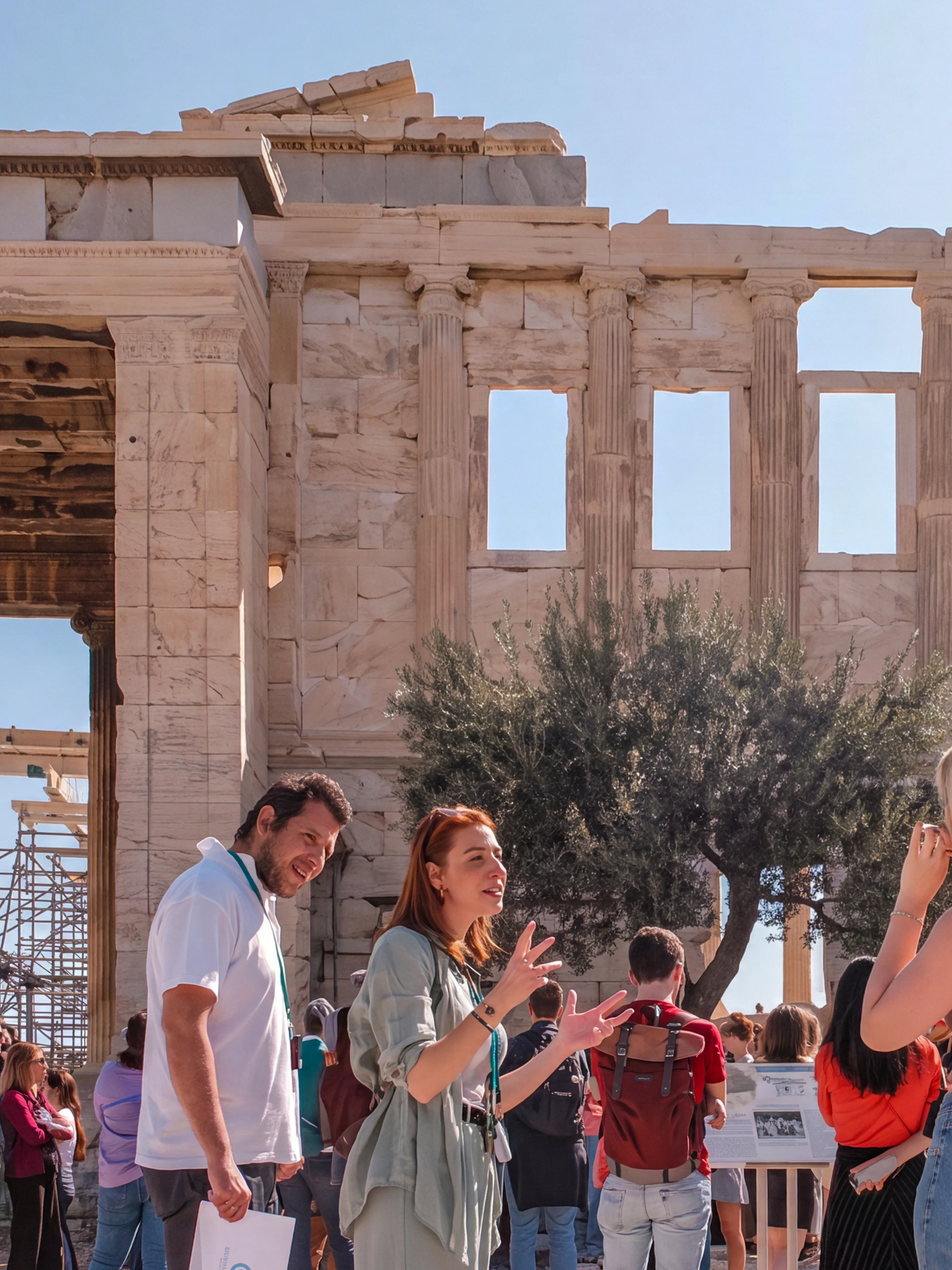 Tour group exploring the Acropolis with a guide in front of the Parthenon, Athens.