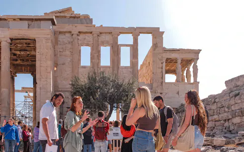 Tour group exploring the Acropolis with a guide in front of the Parthenon, Athens.