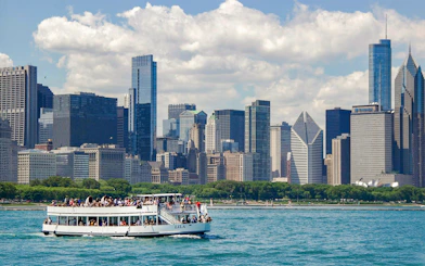 Tour boat on Chicago River with city skyline in background during architecture cruise.