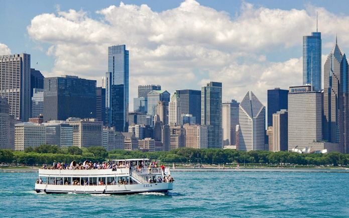 Tour boat on Chicago River with city skyline in background during architecture cruise.