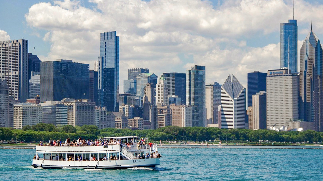 Tour boat on Chicago River with city skyline in background during architecture cruise.