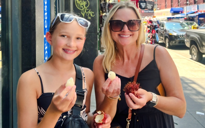 Mom and daughter enjoying lychee on Ahoy New York Food Tour.