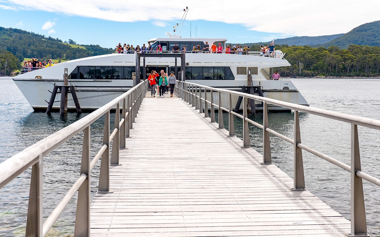 Harbour cruise boat docked at Port Arthur Historic Site with passengers disembarking.