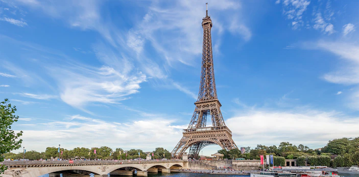 Eiffel Tower view from across the Seine River in Paris, with a boat passing by.