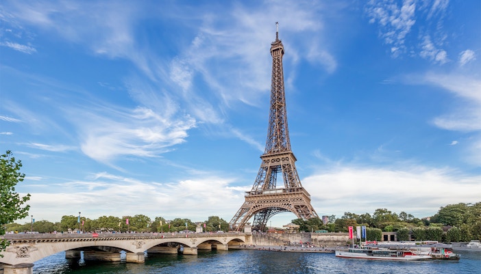 Eiffel Tower view from across the Seine River, Paris, with surrounding cityscape.