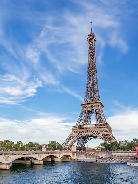 Eiffel Tower view from across the Seine River in Paris, with a boat passing by.