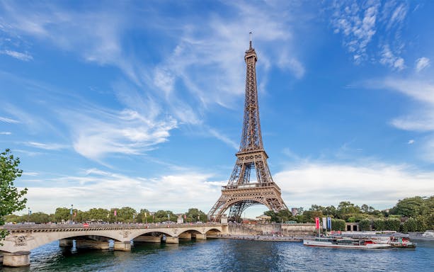 Eiffel Tower view from across the Seine River in Paris, with a boat passing by.