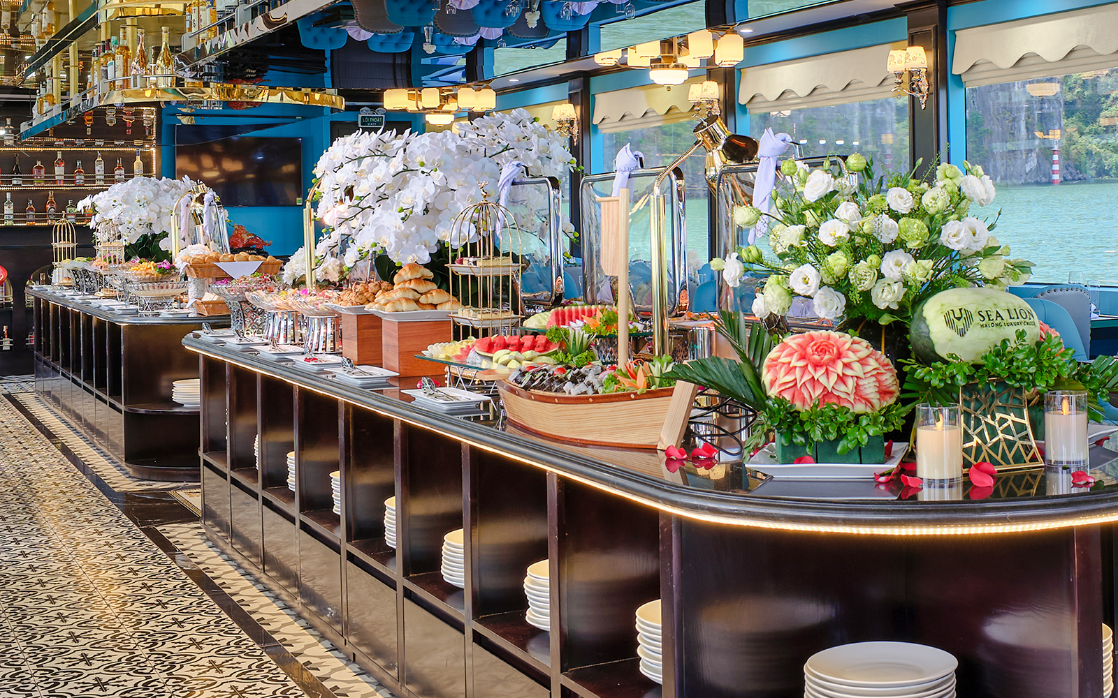 Buffet table with fresh fruits, pastries, and floral arrangements on a cruise ship.