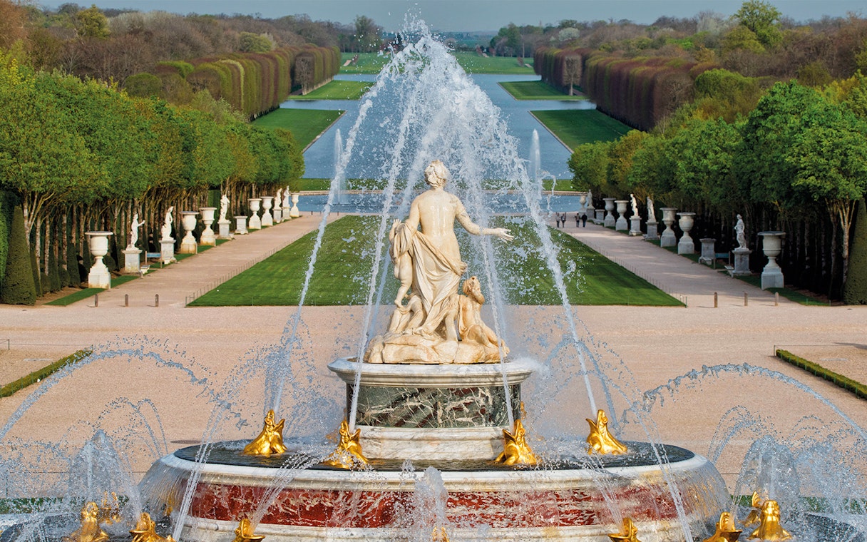 Fountain with statues and water jets at the Palace of Versailles, Paris.